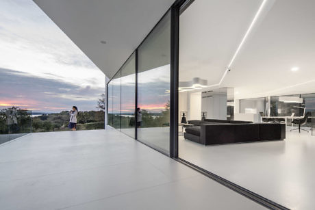 Minimalist interior with floor-to-ceiling windows and sunset view.