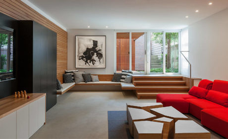 Modern living room with red sofa, wooden steps, and large art piece.