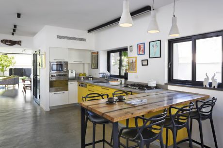 Modern kitchen with yellow accents and a wooden dining table.