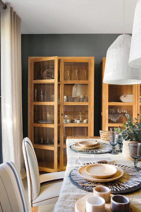 A cozy dining room with a wooden cabinet, set table, and pendant lamps.