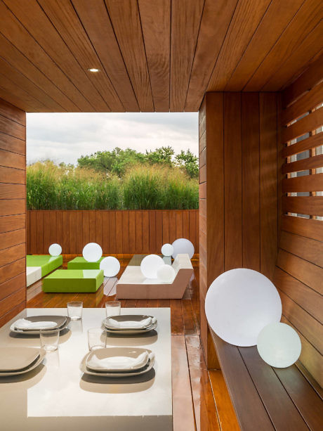 Contemporary dining space with rich wooden paneling and green accents.