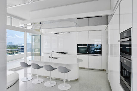 Modern kitchen interior with white cabinets, curved island, and bar stools.