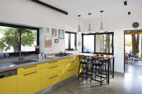 Contemporary kitchen with bright yellow cabinets and sleek pendant lights.
