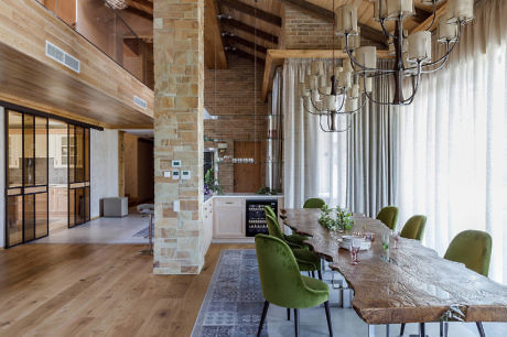 Modern rustic dining room with brick column, wooden table, and chandelier.