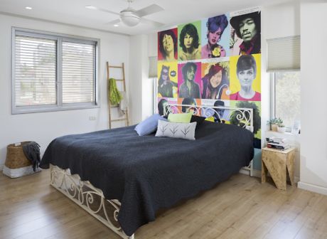 Bedroom with large pop art mural above the bed, hardwood floors, and modern