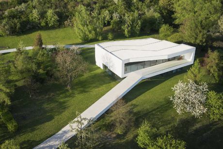 Contemporary house with a sleek white design and an extended walkway, nestled in