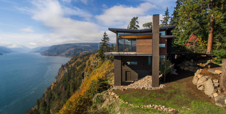 Modern house on a cliff overlooking a scenic river.