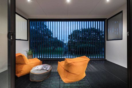 Modern room with two orange chairs, large windows, and a garden view.