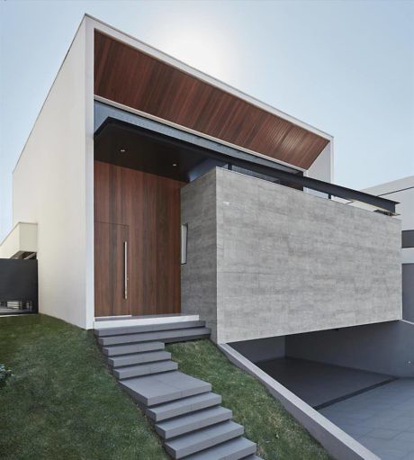 Modern house entrance with wooden door, concrete walls, and floating steps.