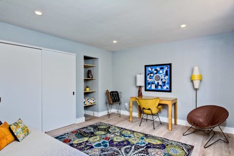 Modern room with desk, chair, colorful rug, and built-in shelves.