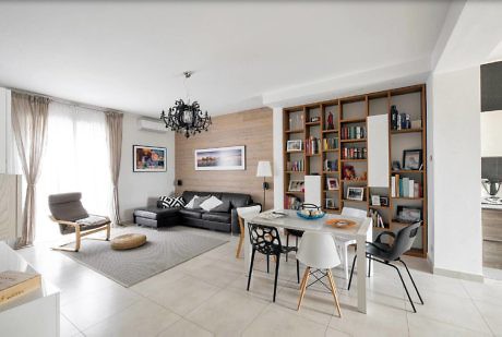 Contemporary living space with sleek furnishings and a bookshelf.