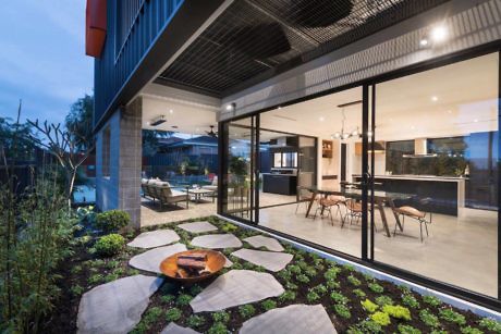 Contemporary home patio with fire pit, large windows, and garden.