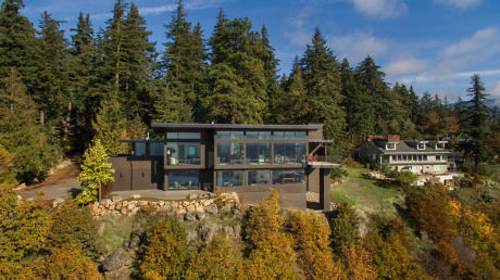 Modern house with large windows surrounded by forest.
