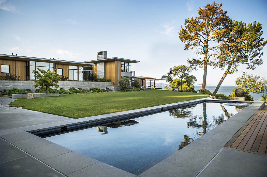 Modern house with large windows, reflecting pool, and ocean view.