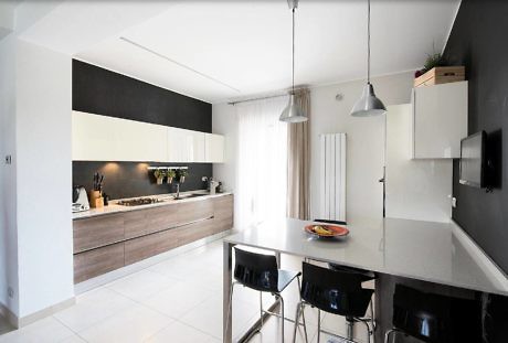 Sleek kitchen with monochrome color scheme and pendant lighting.