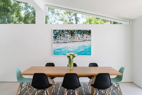 Modern dining room with large window, artwork, and wooden table.