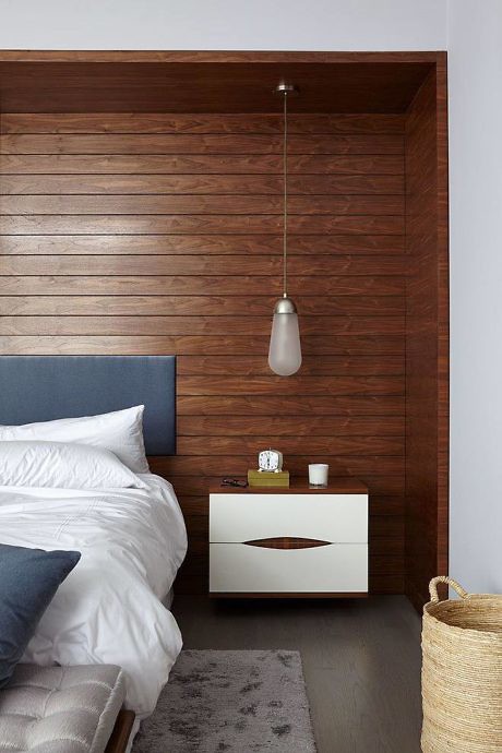 Contemporary bedroom with wooden wall paneling and pendant light.