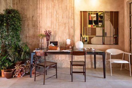 A modern dining room with wooden walls, mixed-style chairs, and abstract art.