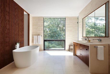 Modern bathroom with a freestanding tub, large window, and wooden vanity.