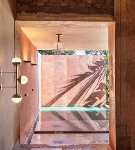 Modern outdoor shower with exposed lighting and shadow patterns on wall.