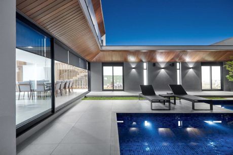 Modern home patio with pool, loungers, and sliding glass doors.