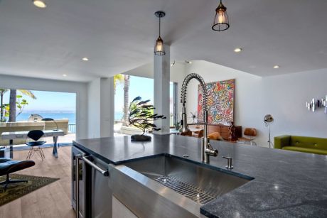 Sleek kitchen interior with ocean view and colorful art.