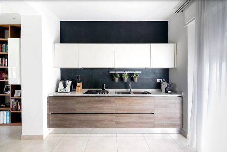 Contemporary kitchen with white cabinets, wood finishes, and a black backsplash.