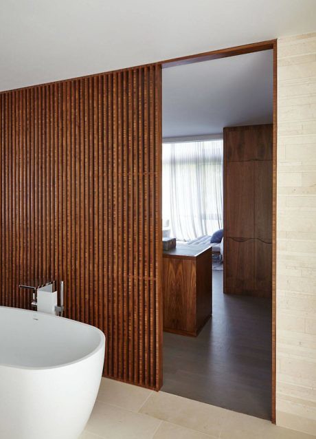 Contemporary bathroom with wooden slat partition and freestanding tub.