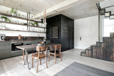 Modern kitchen with wooden dining table, black cabinetry, and concrete ceiling.