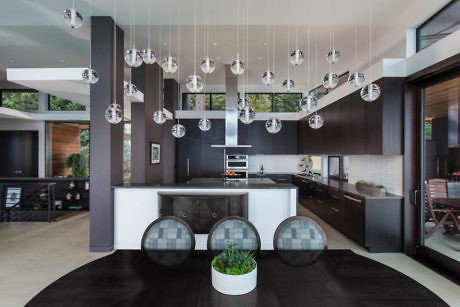 Modern kitchen with hanging spherical lights and dark wood cabinetry.