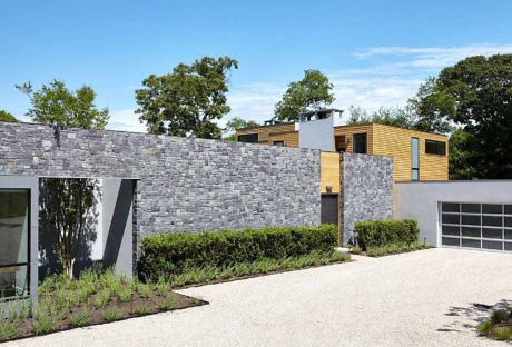 Contemporary house with stone wall and wood paneling.