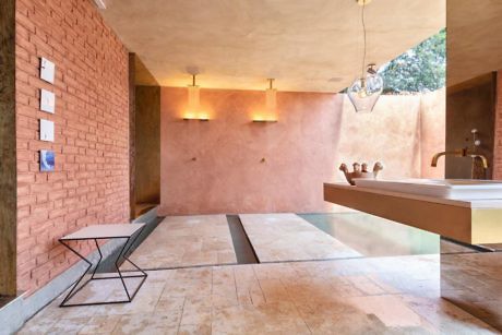 Modern bathroom with exposed brick wall, sleek fixtures, and terracotta tones.