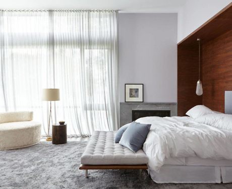 Contemporary bedroom with wooden headboard and sheer curtains.