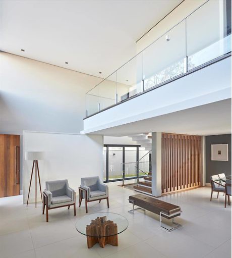 Bright contemporary living room with elevated glass balcony and minimalist furniture.