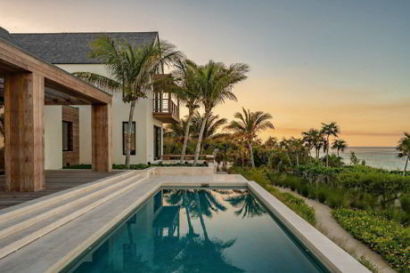 Luxury beachfront home with infinity pool at sunset.