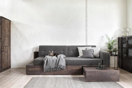 Modern living room with grey sofa, wooden furniture, and white walls.