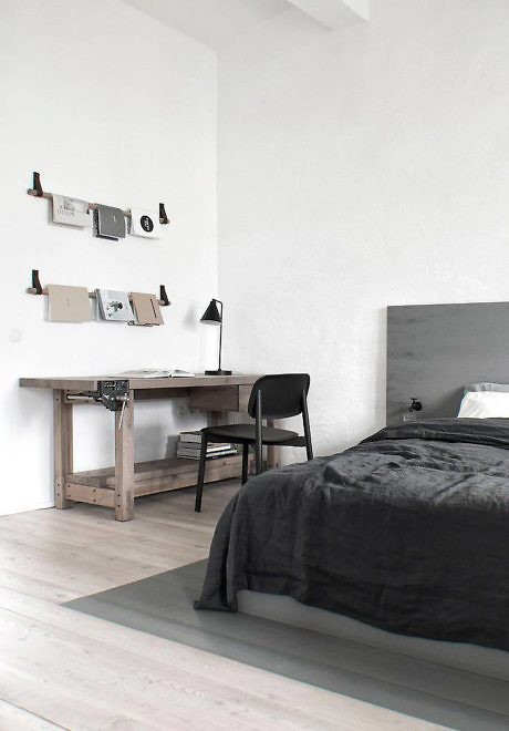 Minimalist bedroom with a bed, desk, and mood board on the wall.