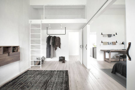 Minimalist interior with white walls, wooden floors, and a loft bed space.