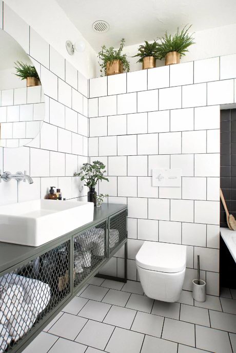 Monochrome tiled bathroom with floating sink and green plants.