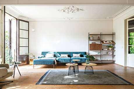 Spacious living room with plush blue sofa, wooden shelving, and decorative pendant lighting.