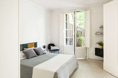 Bright, minimalist bedroom with large windows, neutral tones, and modern furnishings.
