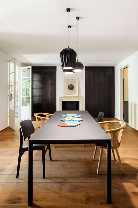 A spacious dining area with modern lighting, dark-colored cabinets, and natural wood furnishings.