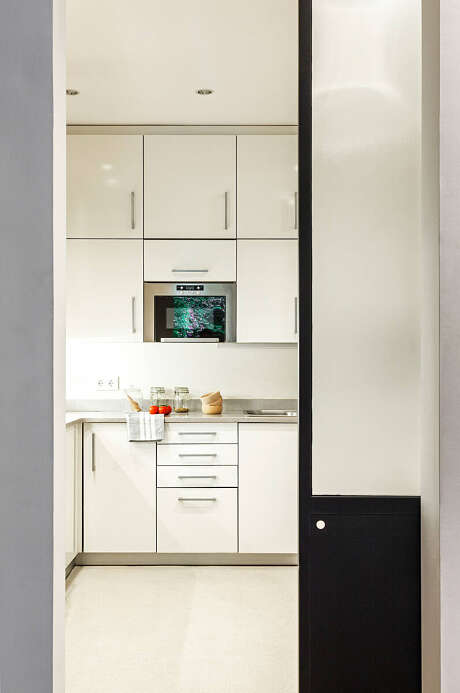 Modern minimalist kitchen with sleek, white cabinetry, a built-in oven, and a black accent wall.