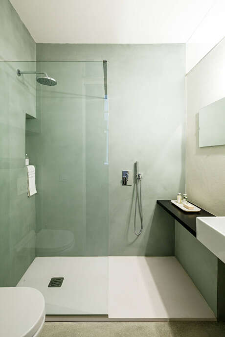 Minimalist bathroom with floor-to-ceiling green tiles, wall-mounted vanity, and glass shower enclosure.