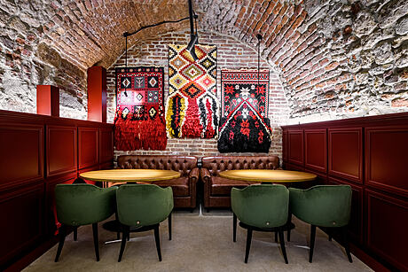 A cozy, ornately decorated dining space with intricate textiles, brick walls, and leather seating.