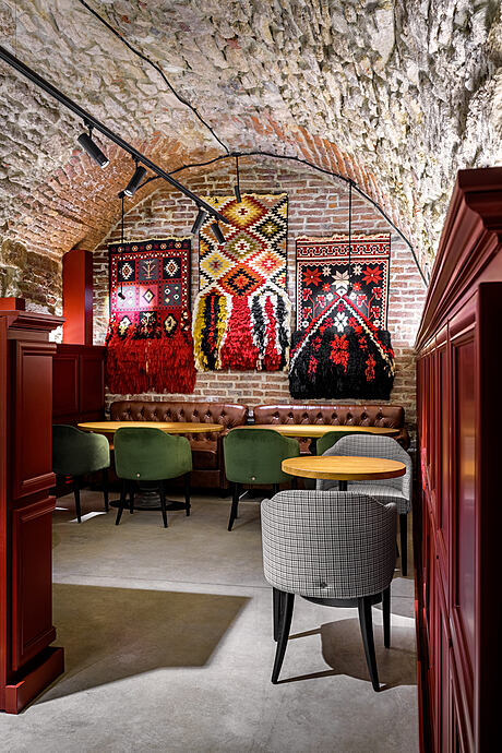 Vibrant textiles adorn the rustic brick walls, complementing the cozy furnishings and lighting.