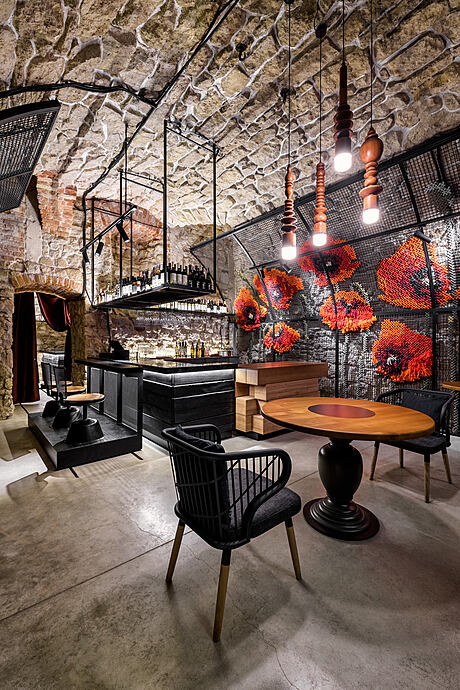 A cozy restaurant with exposed stone walls, modern lighting, and eclectic furniture.