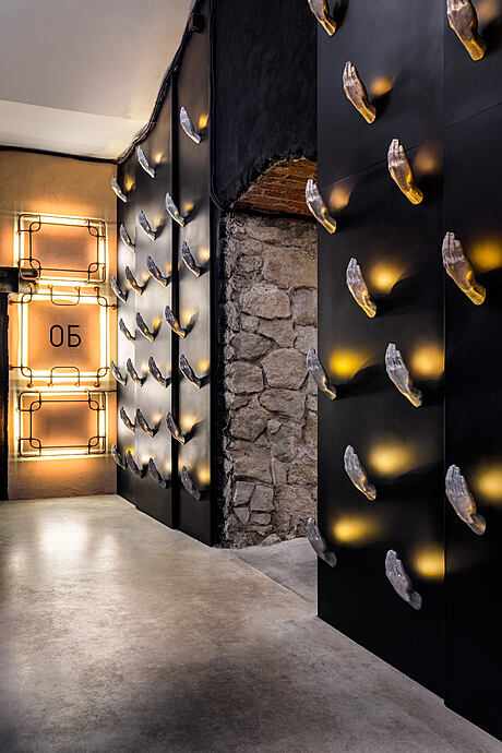 A dimly lit hallway with stone walls, golden lighting fixtures, and eerie floating crystal-like forms.