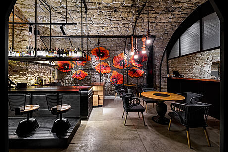 A cozy, dimly lit cafe with exposed brick walls, modern decor, and vibrant floral art.