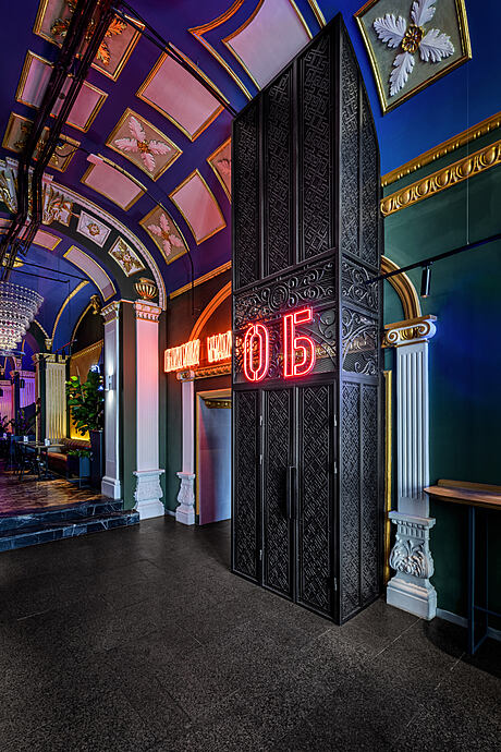 Ornate, colorful architectural interior with intricate design elements and neon display.